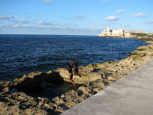Coast in Havana with people jumping into the water holding hands