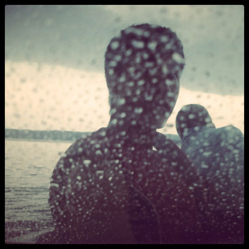 Boy on a boat at dusk through a rain spattered window